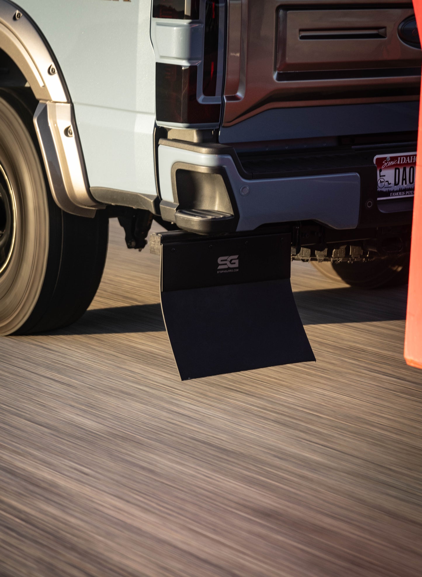 Dynamic view of the receiver hitch-mounted Step N Guard mud flap providing stability and protecting the attached trailer during high-speed travel.