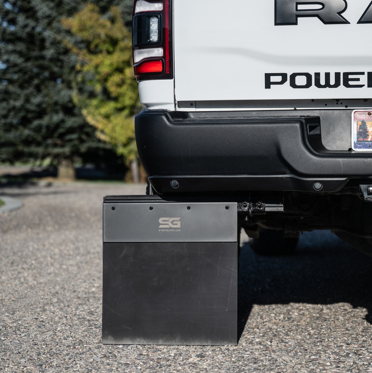 a step and mud flap system with the logo on the anti-sail plate mounted to a dodge ram